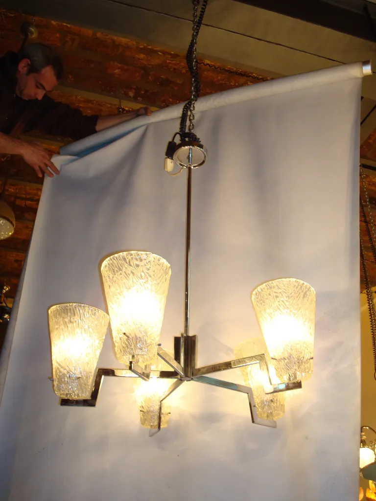 Lâmpada de teto antiga com cinco luzes brilhantes, criando um ambiente acolhedor.