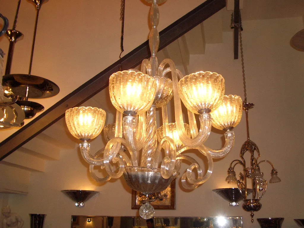 lustre ancien avec bras courbés et ampoules allumées.