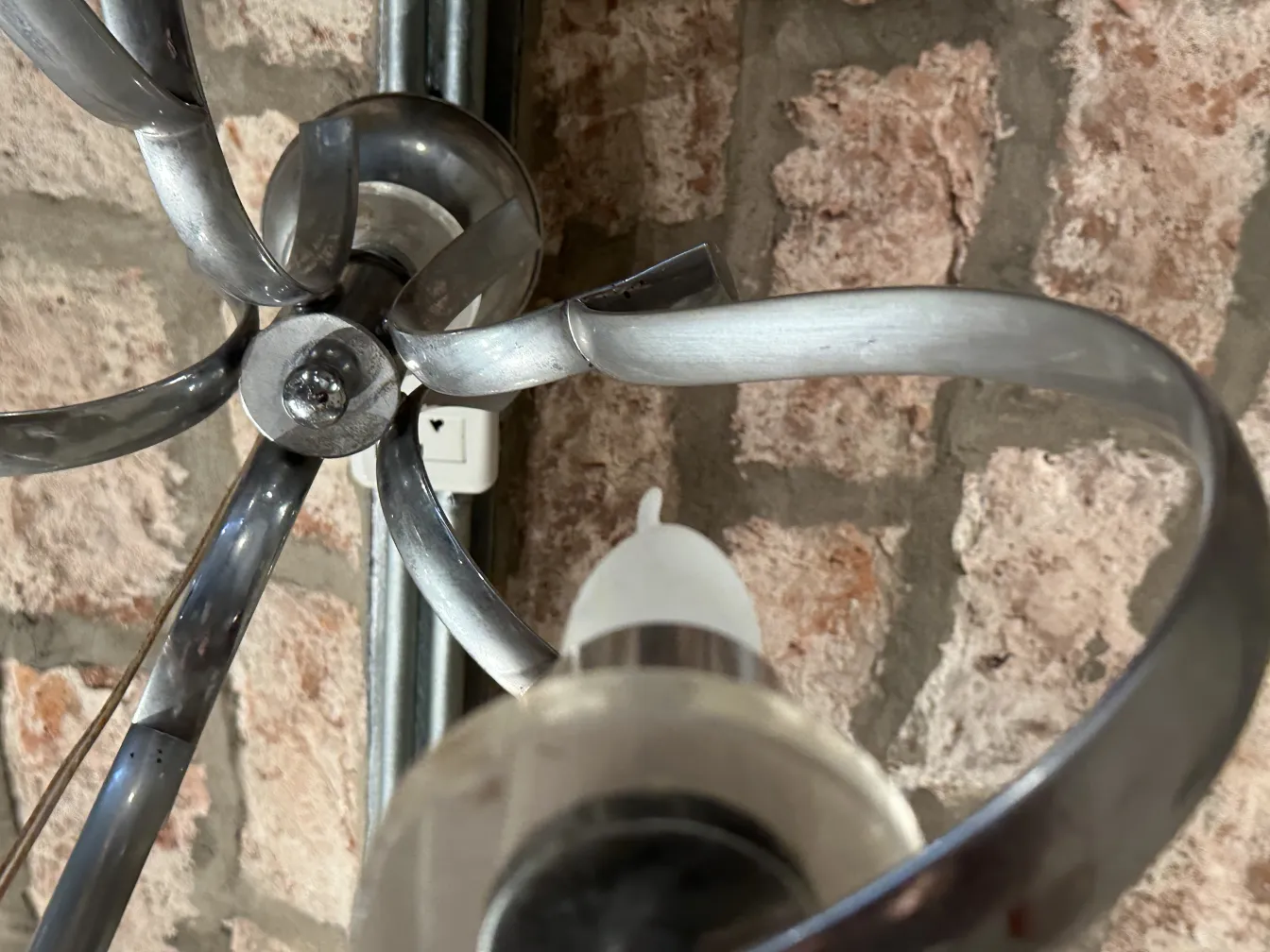 Lâmpada de teto antiga com braços curvados e detalhes decorativos em um ambiente rústico