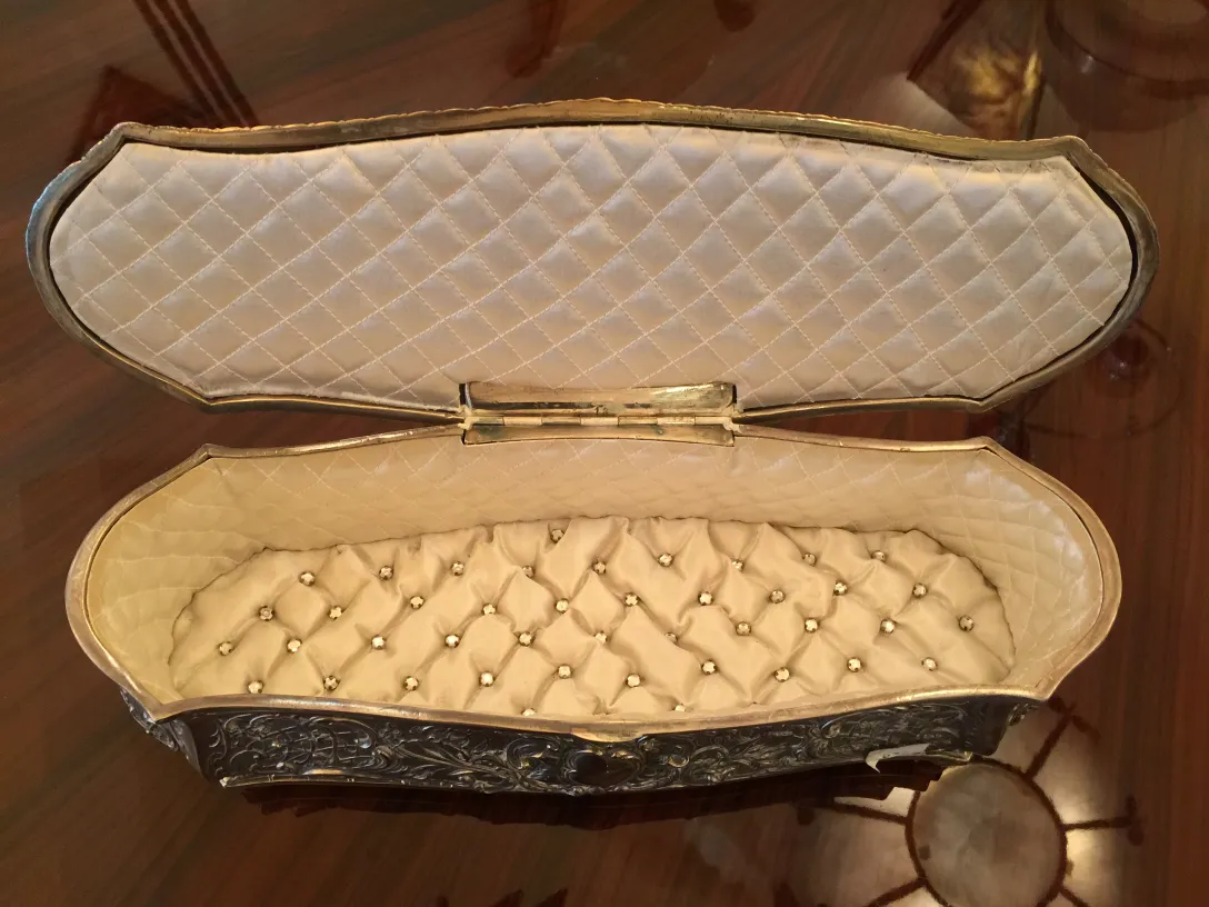 Antique box featuring a padded interior and decorative details.