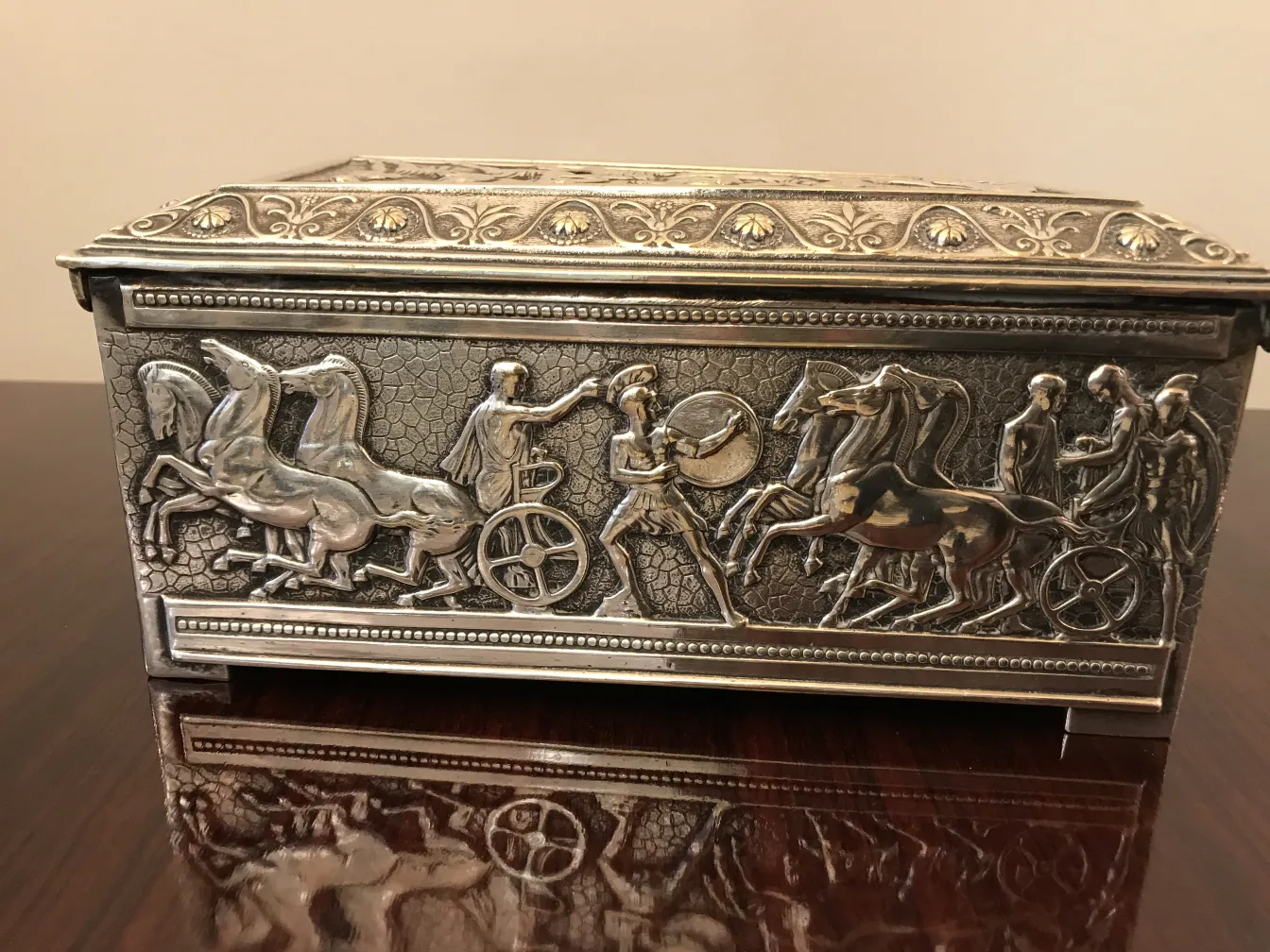 Antique box with reliefs of classical scenes featuring horses and figures.