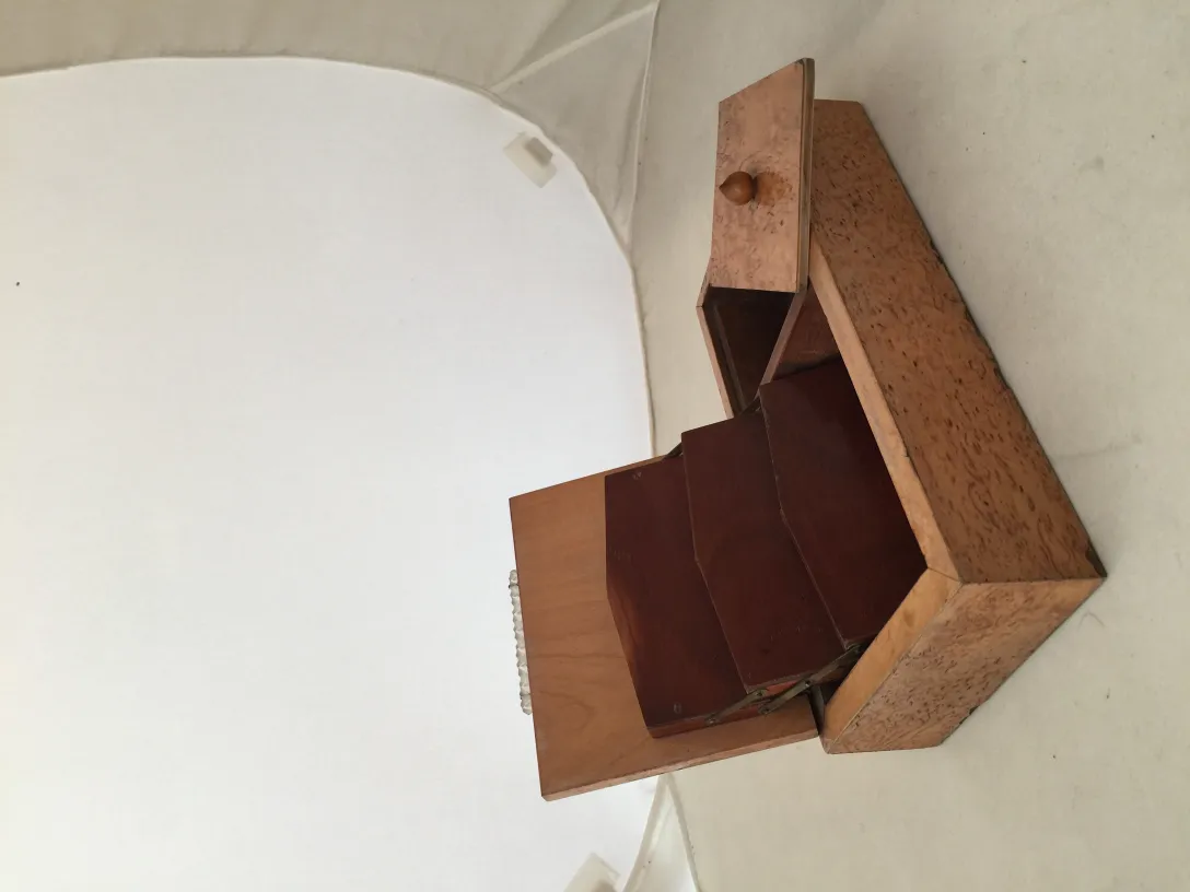 Caja antigua de madera con compartimentos internos en un ambiente neutral.