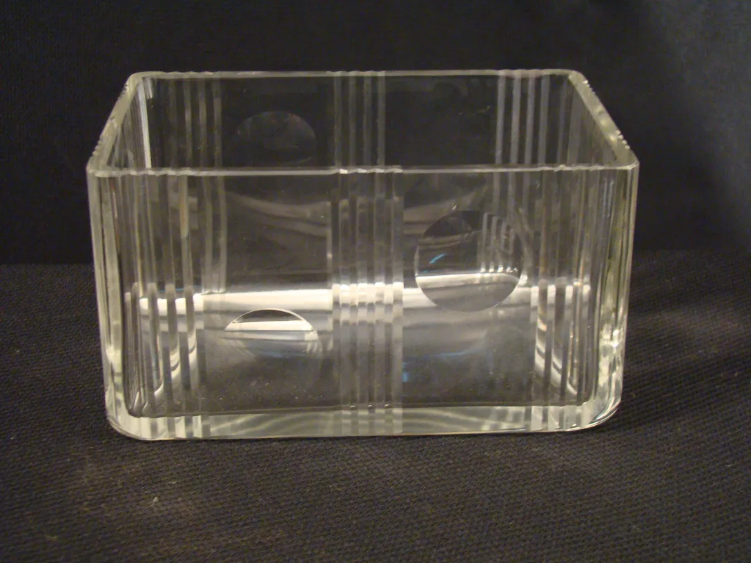 Caja antigua de cristal transparente con líneas verticales y círculos.