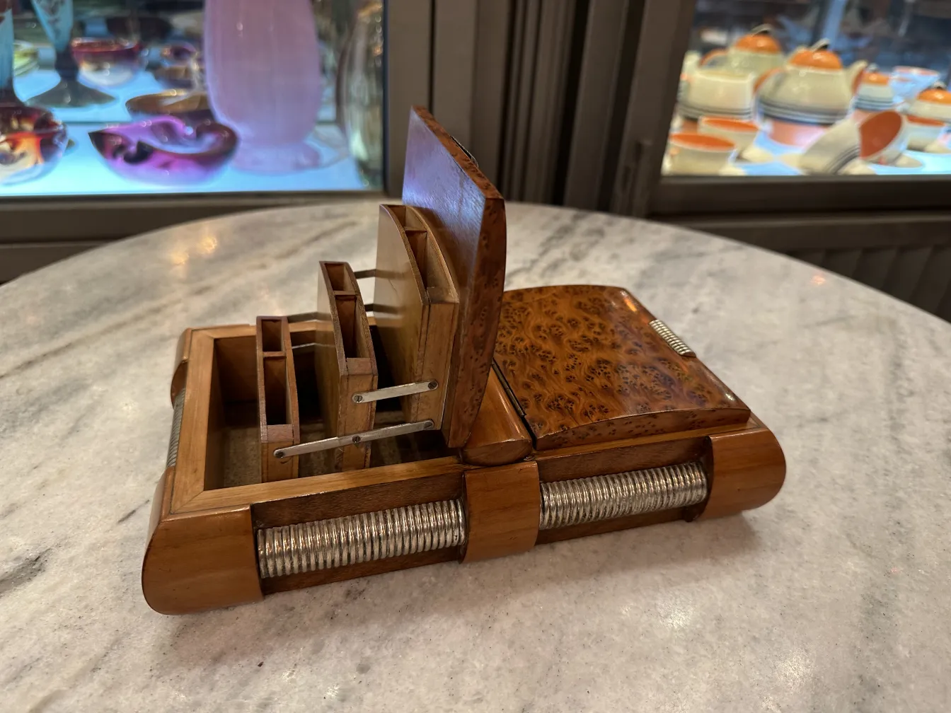 Caja antigua de madera con compartimentos y detalles decorativos, exhibida en un entorno elegante.