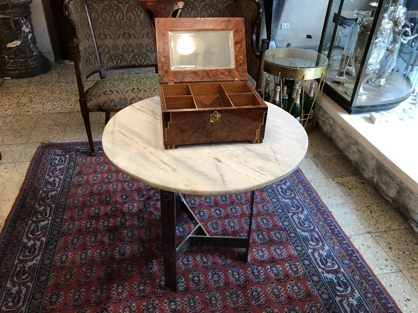 Boîte ancienne avec un miroir sur le couvercle, posée sur une table.