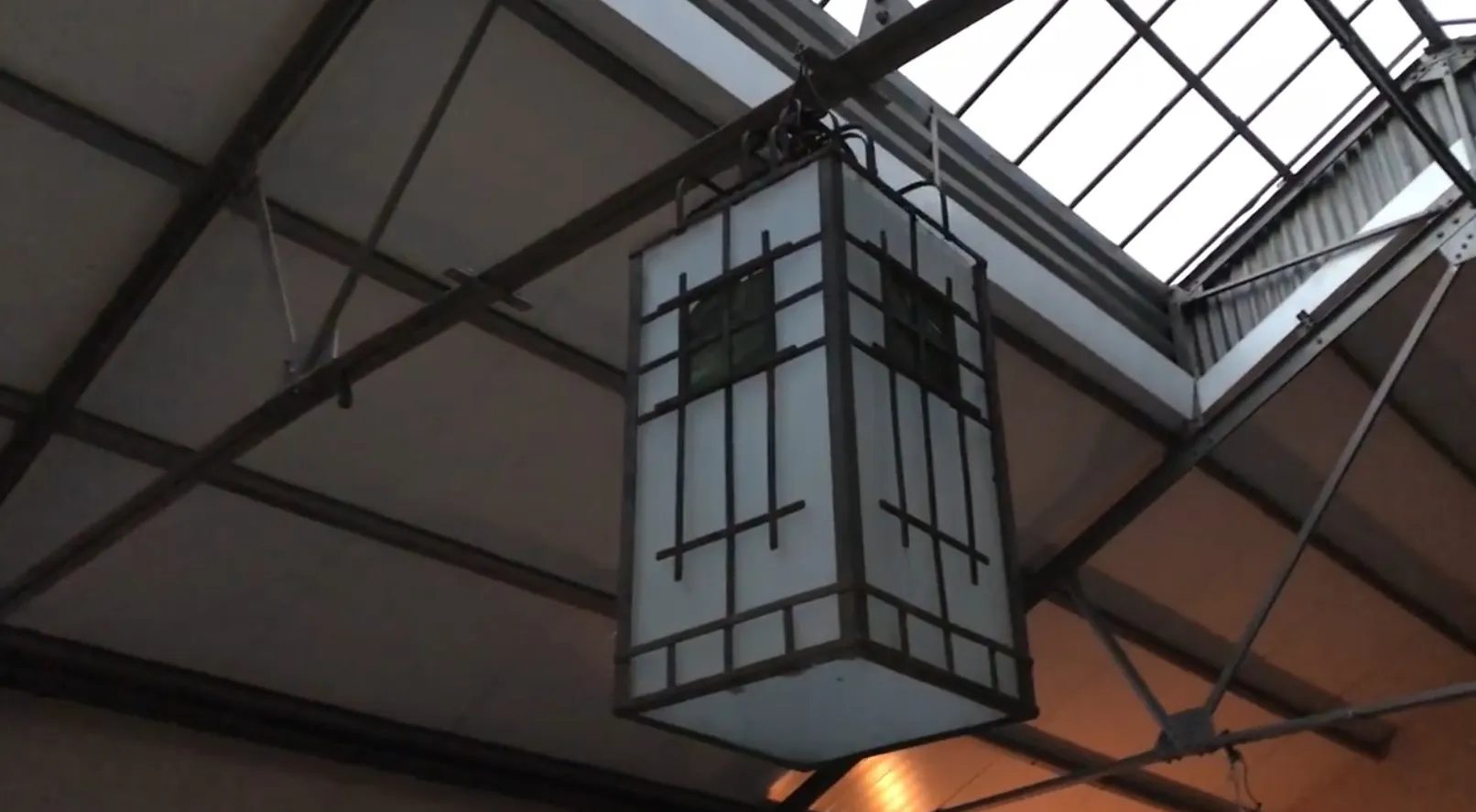 Two antique ceiling lanterns hanging in an industrial setting.