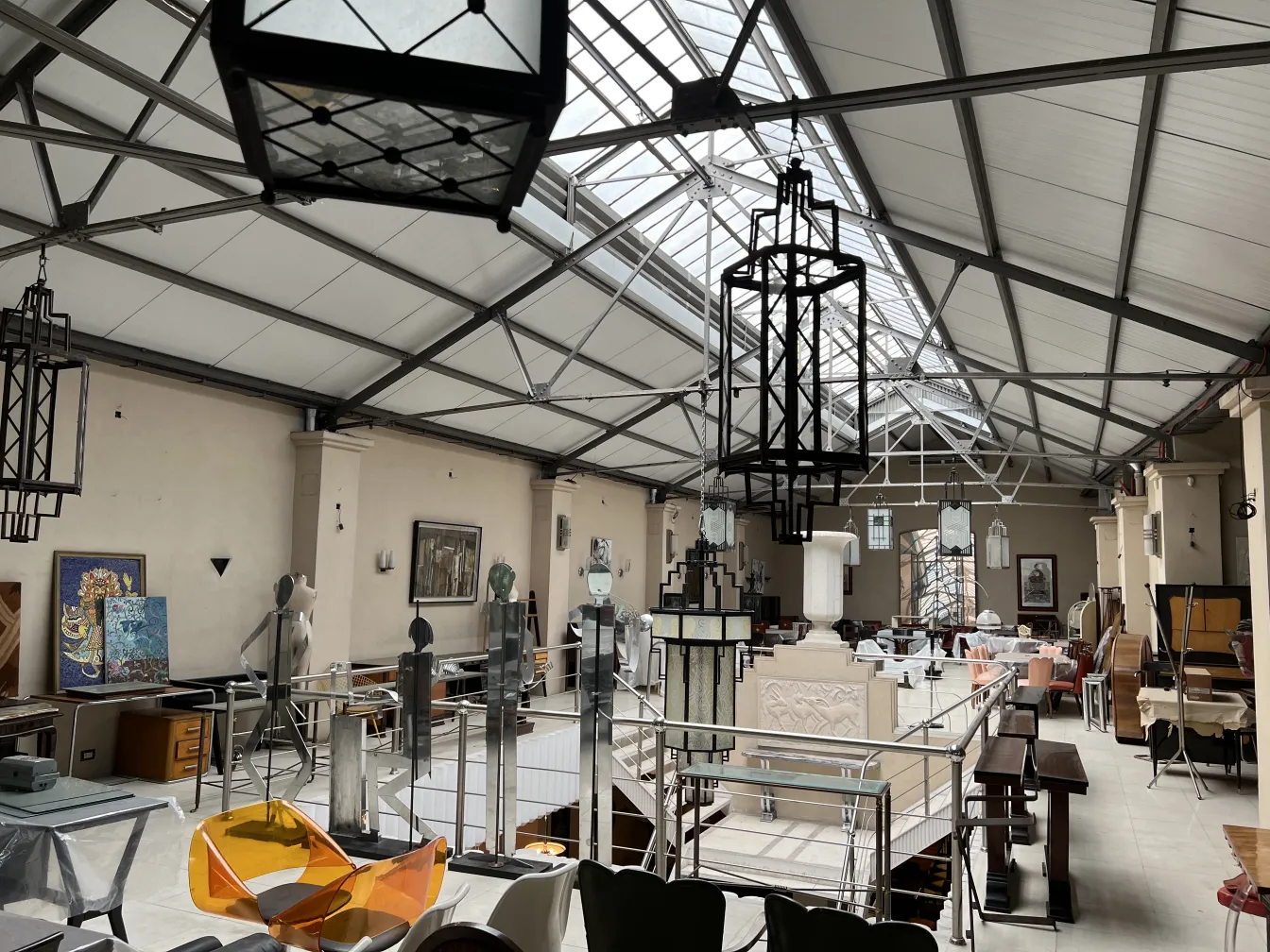 Two antique lanterns hanging in a spacious industrial setting, with mechanical details in the background.