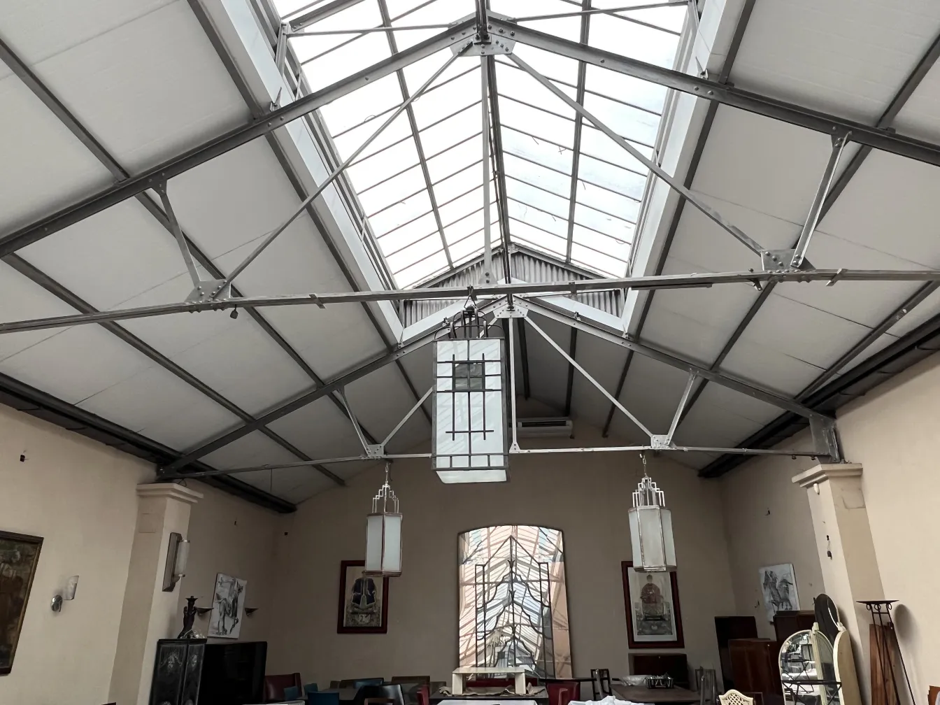 Deux lanternes anciennes suspendues dans un grand espace avec un toit en verre.