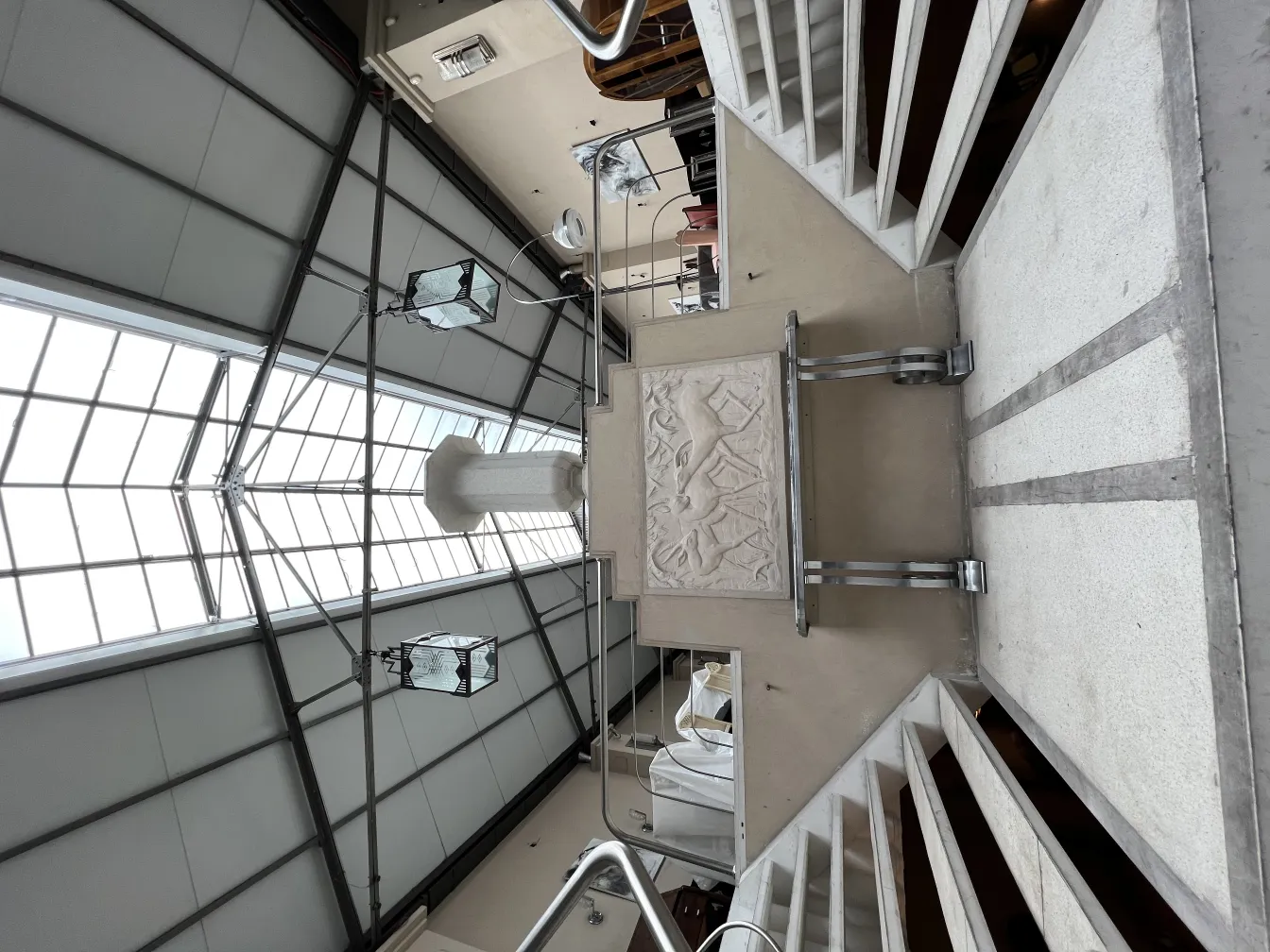 Two hanging antique lanterns in a modern indoor space with stairs.