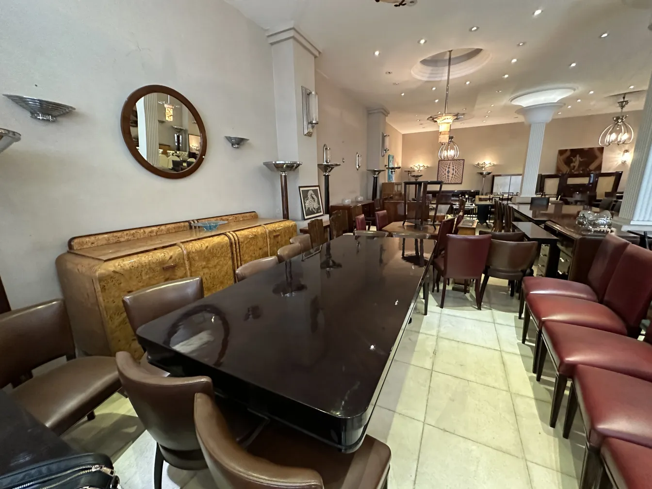 Aparador antiguo con acabado de madera, rodeado de sillas en un ambiente elegante.