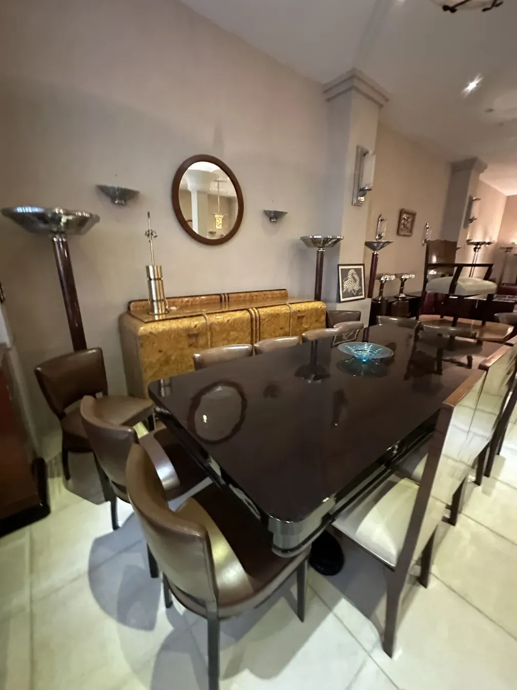 Credenza antica con dettagli eleganti in ambiente moderno, circondata da sedie e specchi.