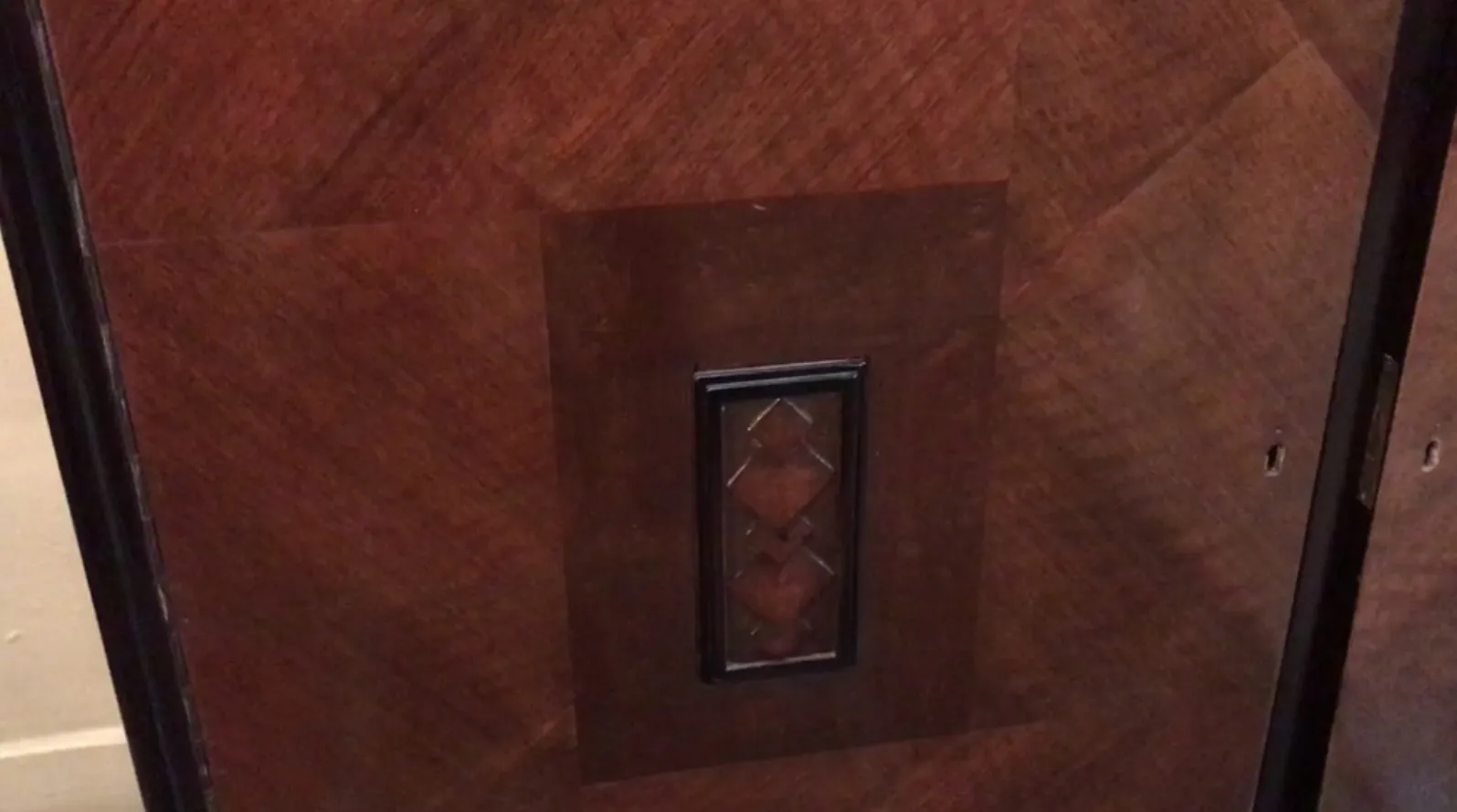 Aparador antigo com detalhes decorativos em tons escuros e design elegante.