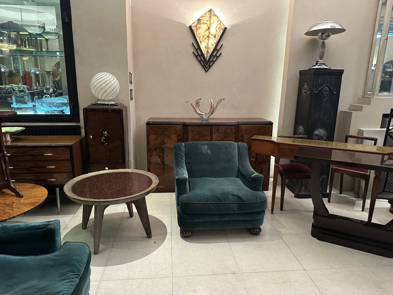 Aparador antigo com detalhes elegantes, ao lado de cadeiras e uma mesa, em um ambiente sofisticado.