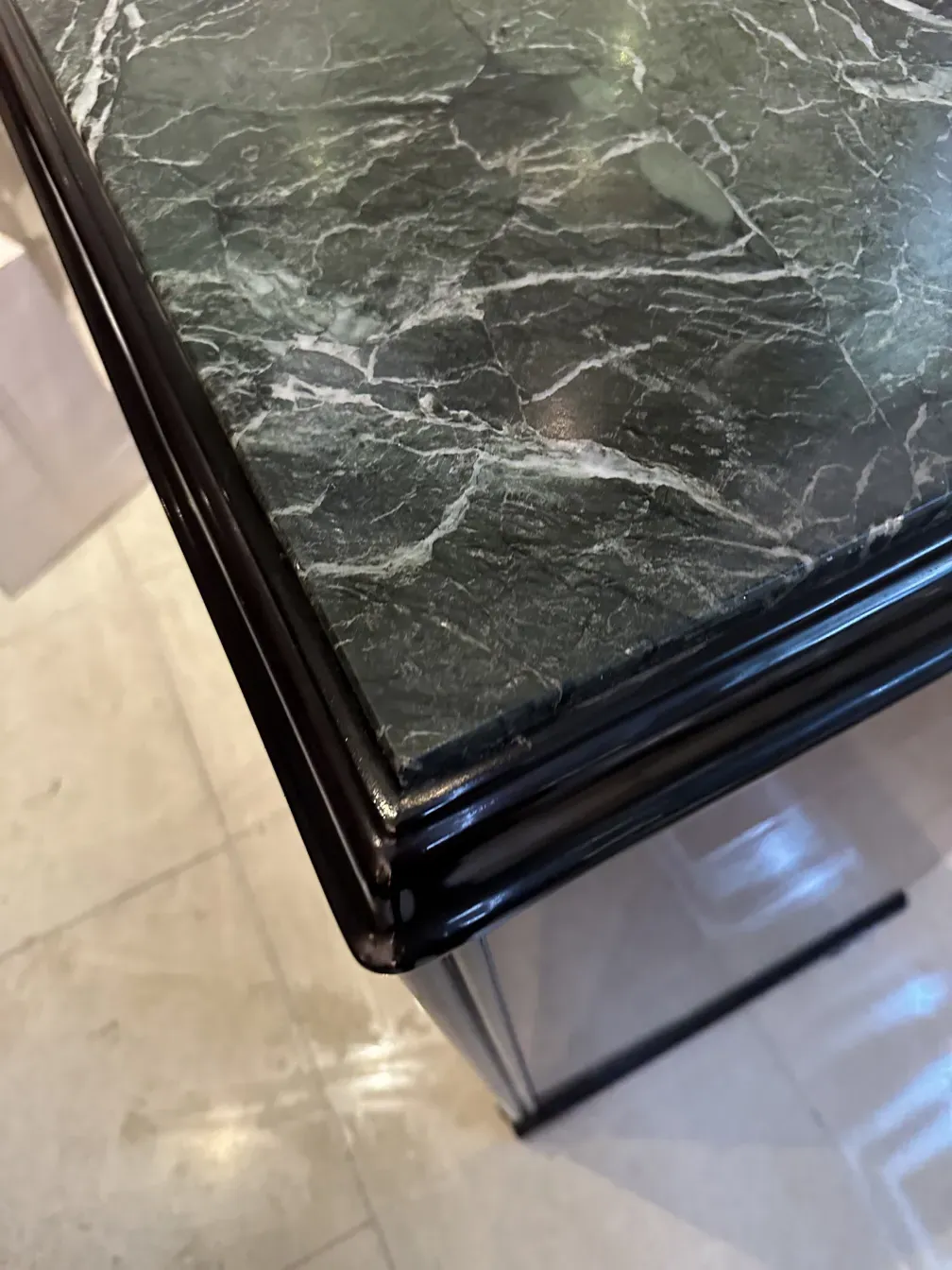 Credenza antica con superficie decorativa in marmo e angoli arrotondati.