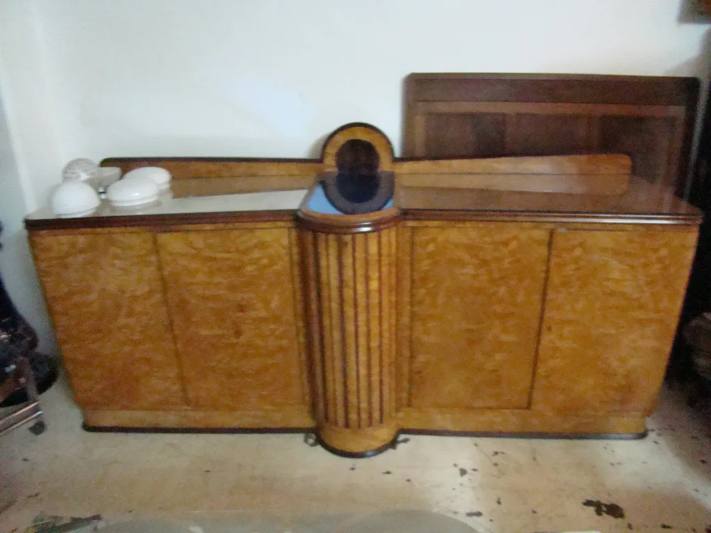 Credenza antica con design curvo e dettagli sottili, decorata con stoviglie bianche.