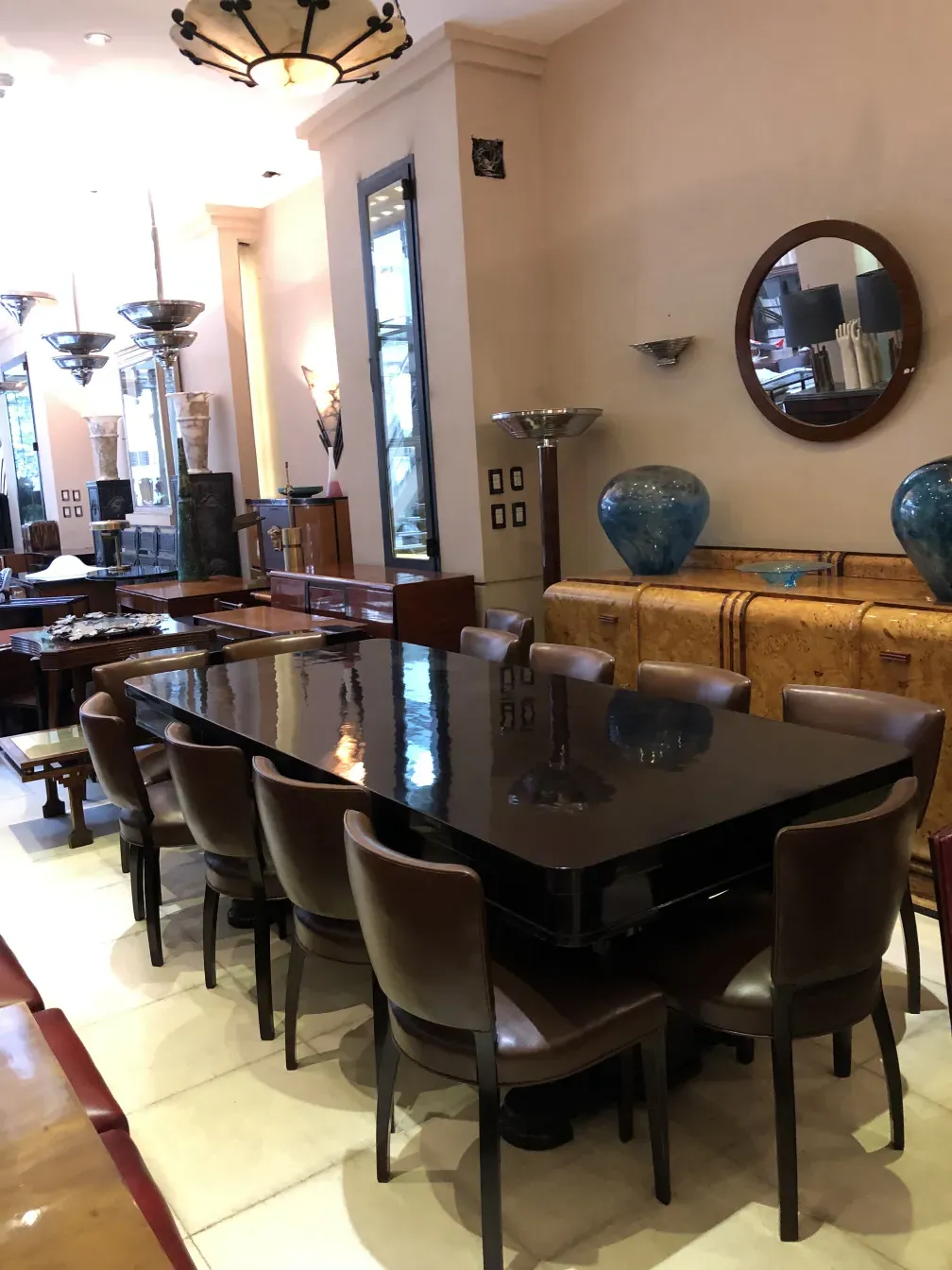 Vaisselier ancien avec design décoratif, entouré de chaises et lampes.