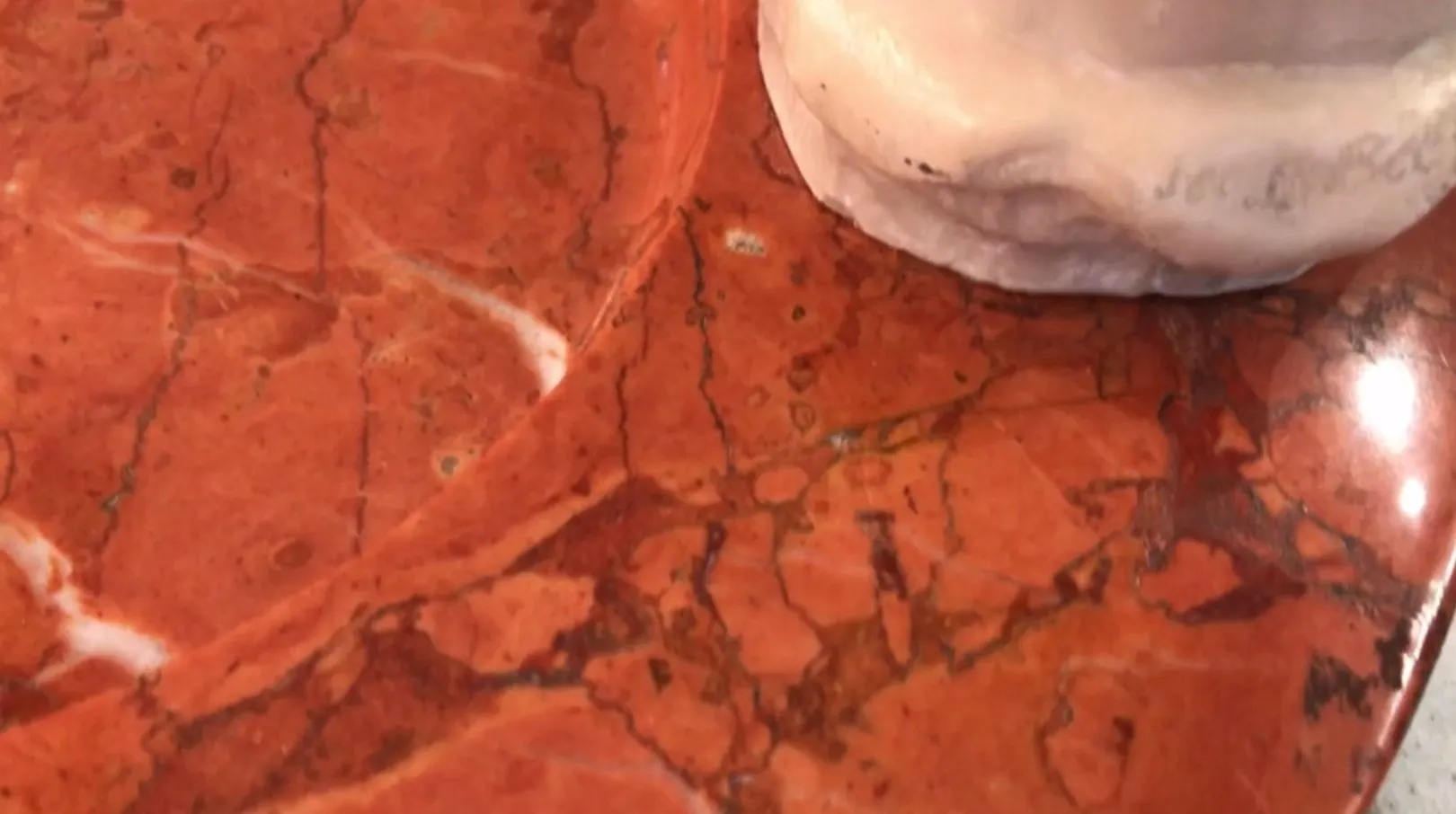 Posacenere in piedi antico con dettagli decorativi su superficie rossa.