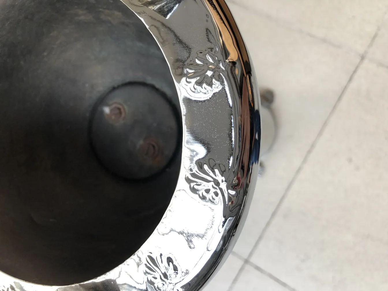 Cinzeiro de pé antigo com detalhes decorativos em fundo neutro.