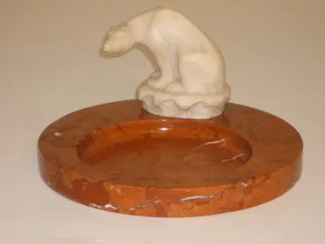 Antiker stehender Aschenbecher mit dekorativer Figur oben, neutraler Hintergrund.