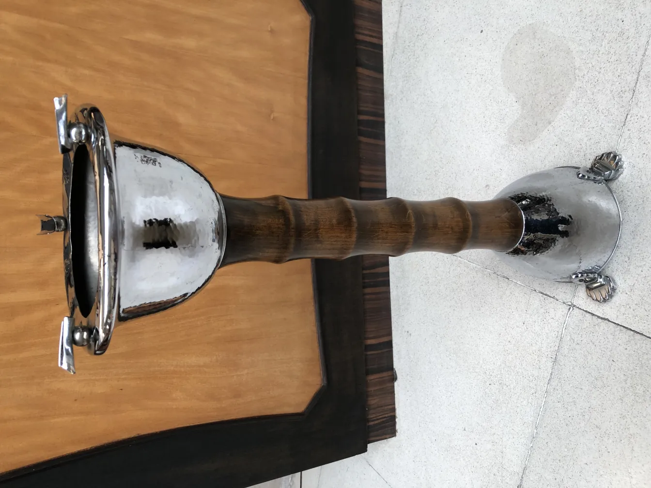 Cinzeiro de pé antigo com design elegante, fundo claro.