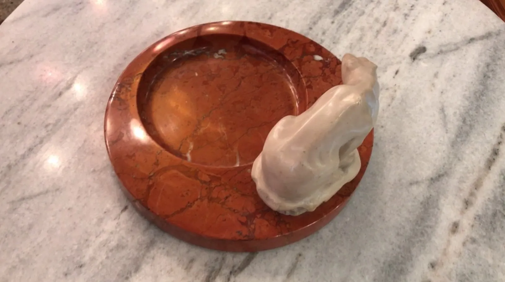 Standing ashtray on a marble table, brown color with elegant shape.