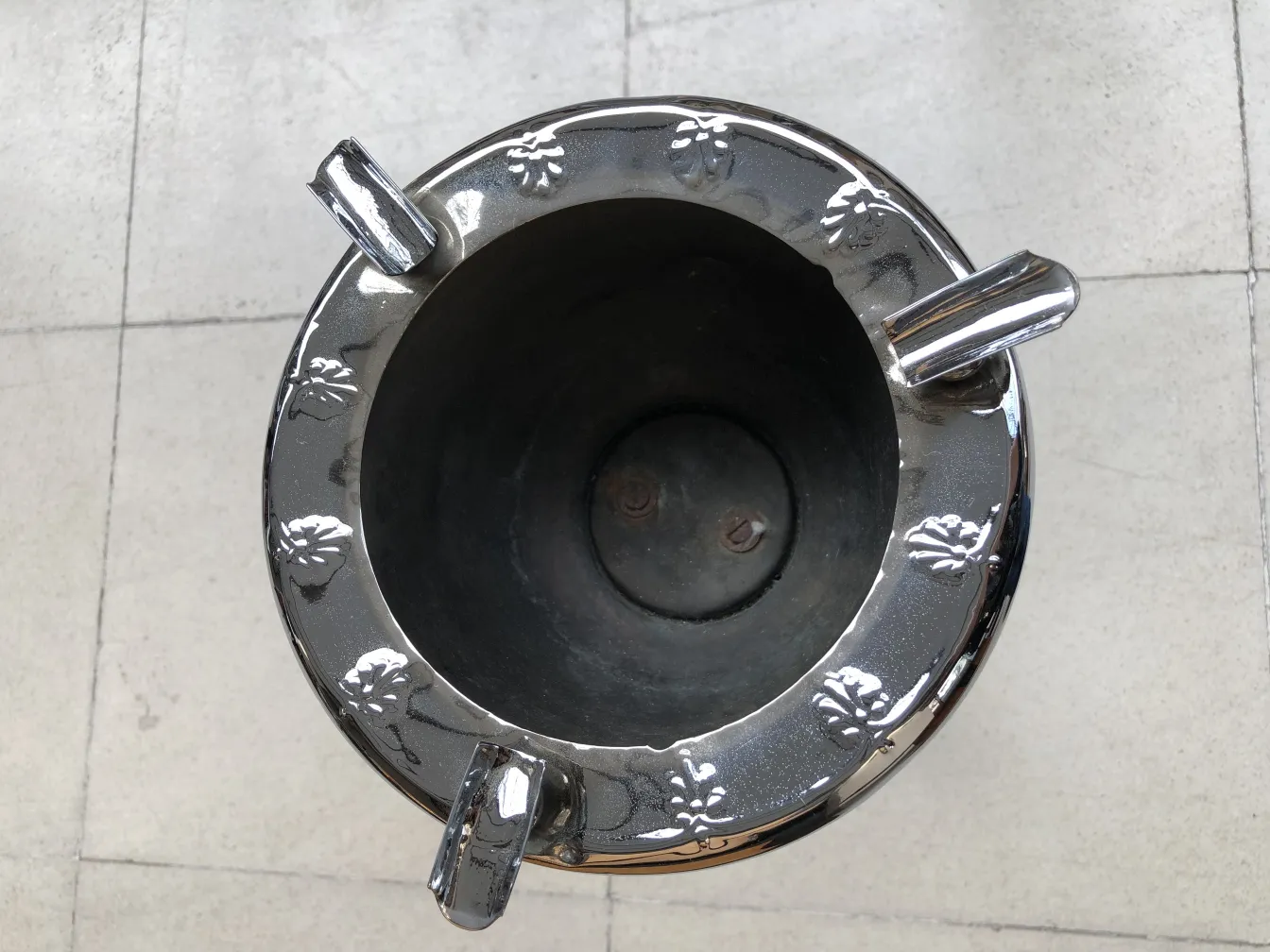 Antique standing ashtray with rose design on the edge.