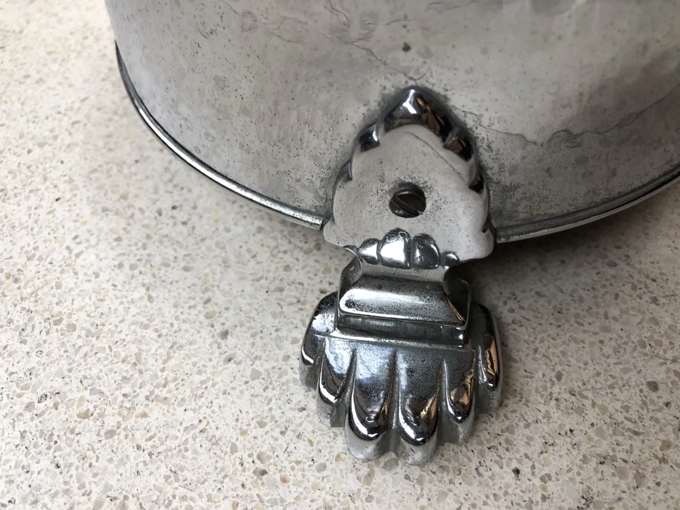 Antique standing ashtray with a decorative claw base on a light surface.
