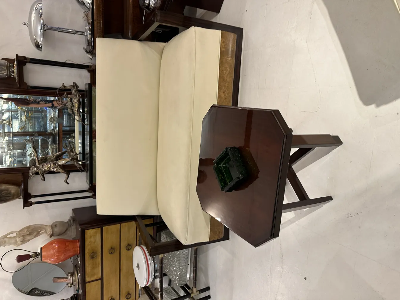 लकड़ी की मेज पर प्राचीन खड़ी ऐशट्रे, पुराने फर्नीचर से घिरी हुई।