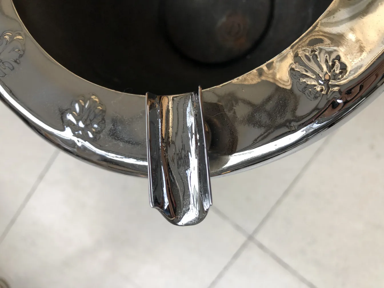 Cinzeiro de pé antigo com bonitos detalhes decorativos na parte superior, colocado sobre um fundo claro.