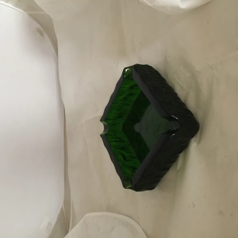 Cenicero de pie antiguo de forma única con tonos verdes, en fondo claro.