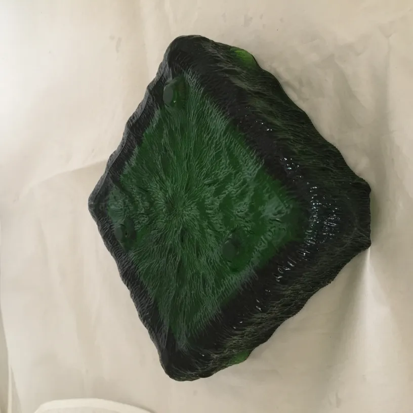 Cenicero de pie antiguo de color verde con diseño atractivo, rodeado de elementos decorativos