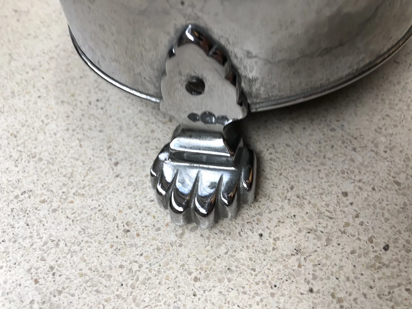 Cendrier sur pied ancien avec base décorative dans un cadre neutre.