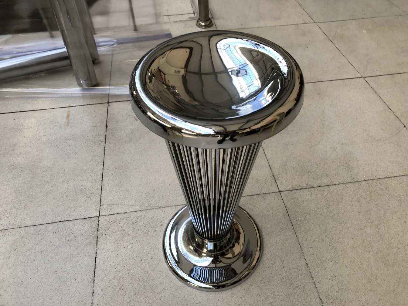 cinzeiro de pé antigo com design elegante e polido de warren platner, em um ambiente moderno.