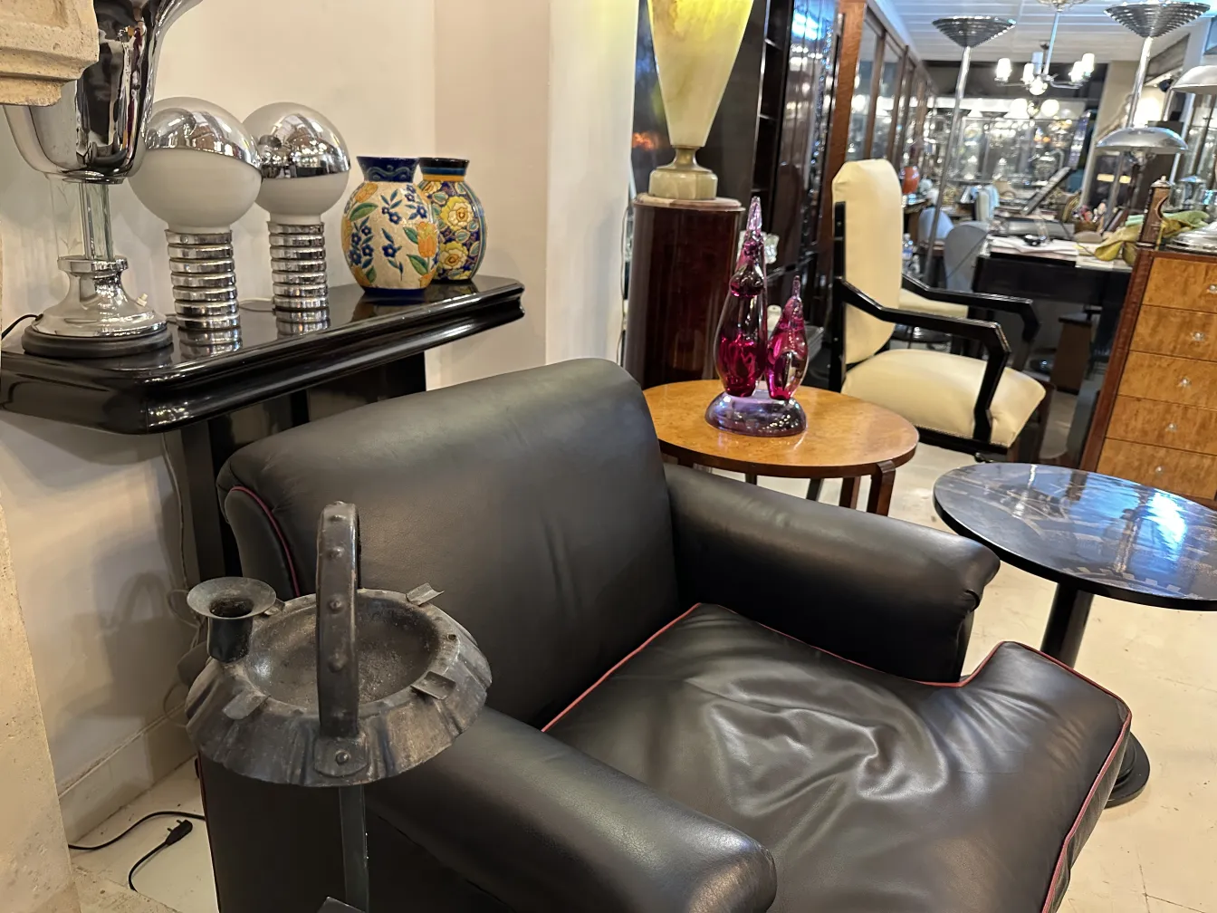 Cinzeiro de pé antigo em um ambiente elegante com outros objetos decorativos.