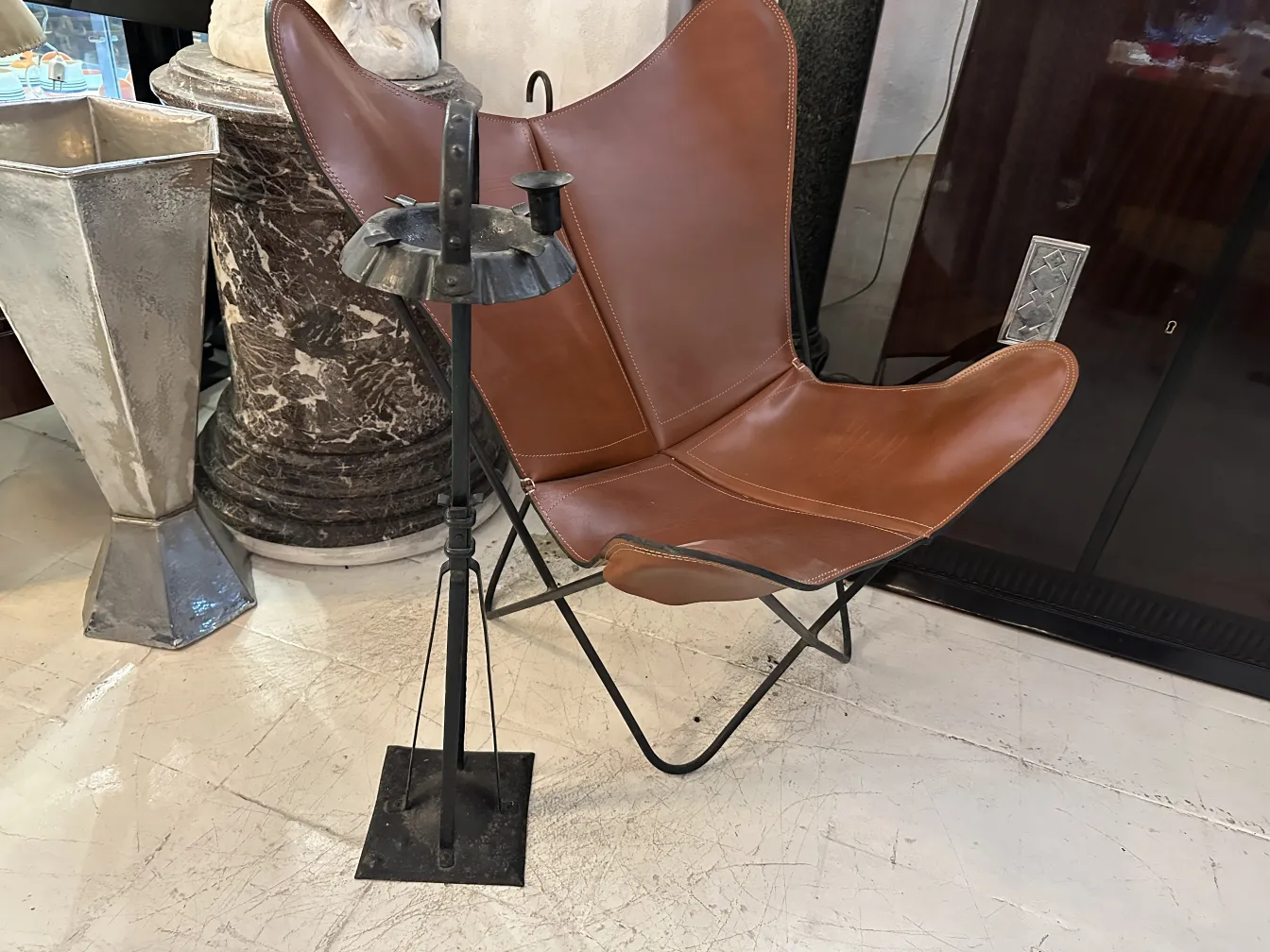 Cenicero de pie antiguo junto a una silla de cuero marrón
