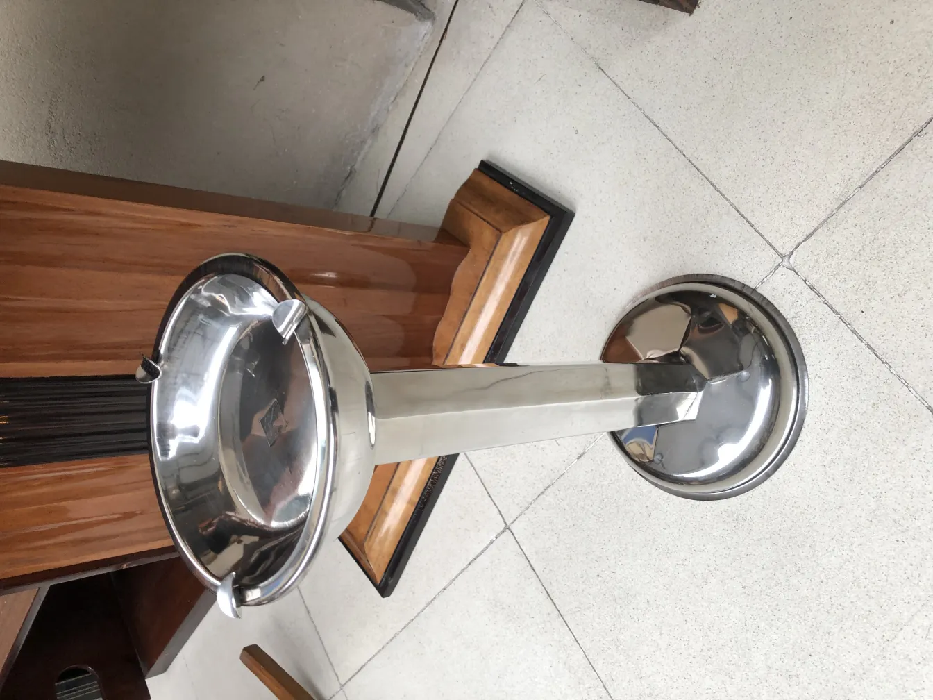 Antique standing ashtray, shiny and functional in a cozy setting.