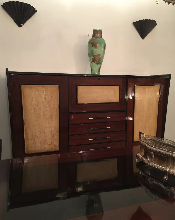 Antique wooden bookcase with shelves and a decorative vase on top.