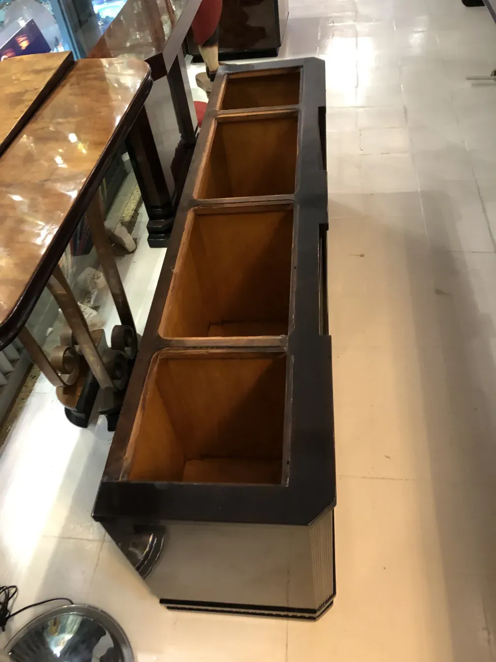 Estante de livros antigo com prateleiras de tamanhos variados e detalhes decorativos, em um ambiente clássico.