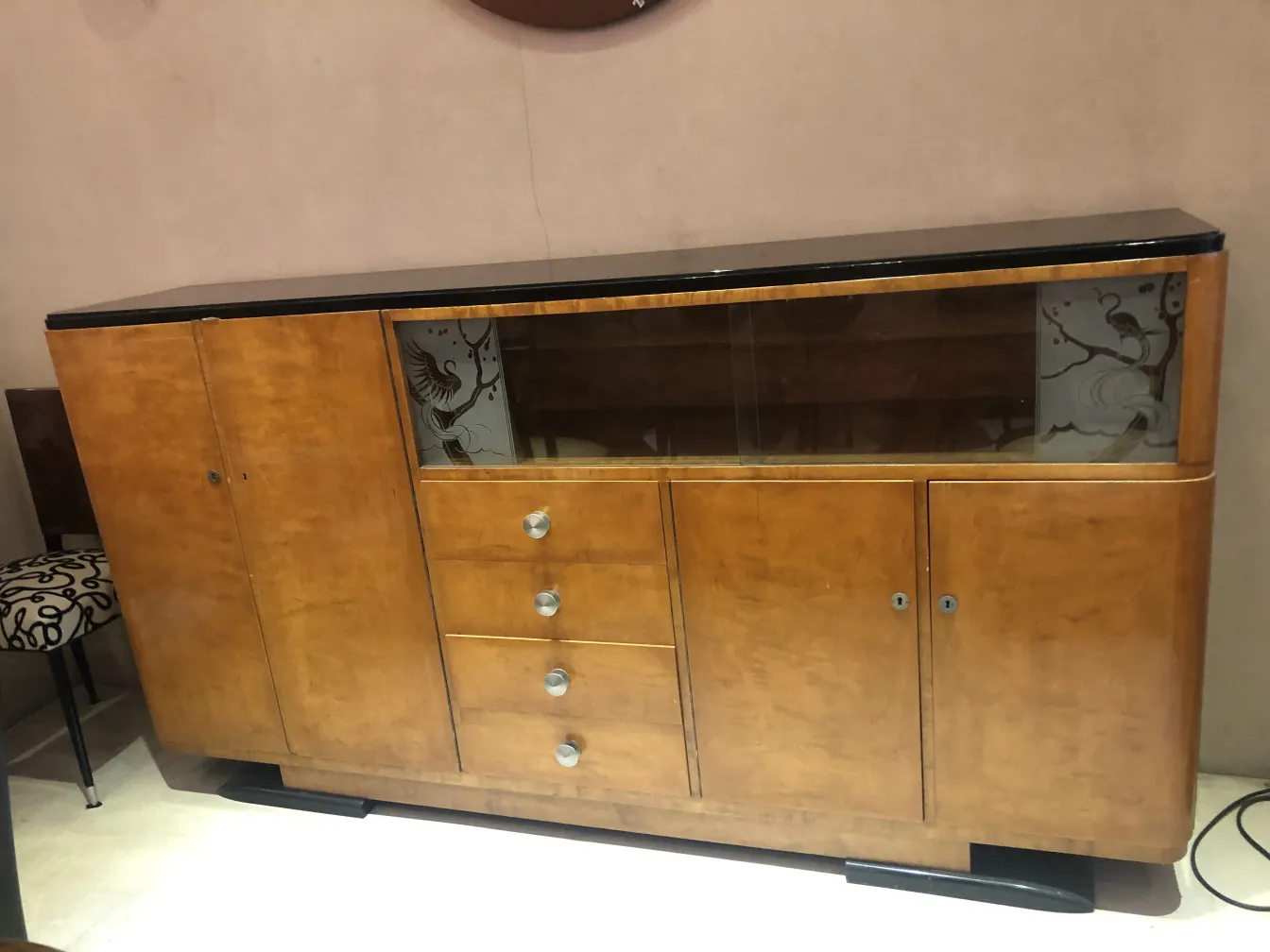 Bibliothèque ancienne avec des détails en verre et des poignées en métal dans un cadre raffiné.