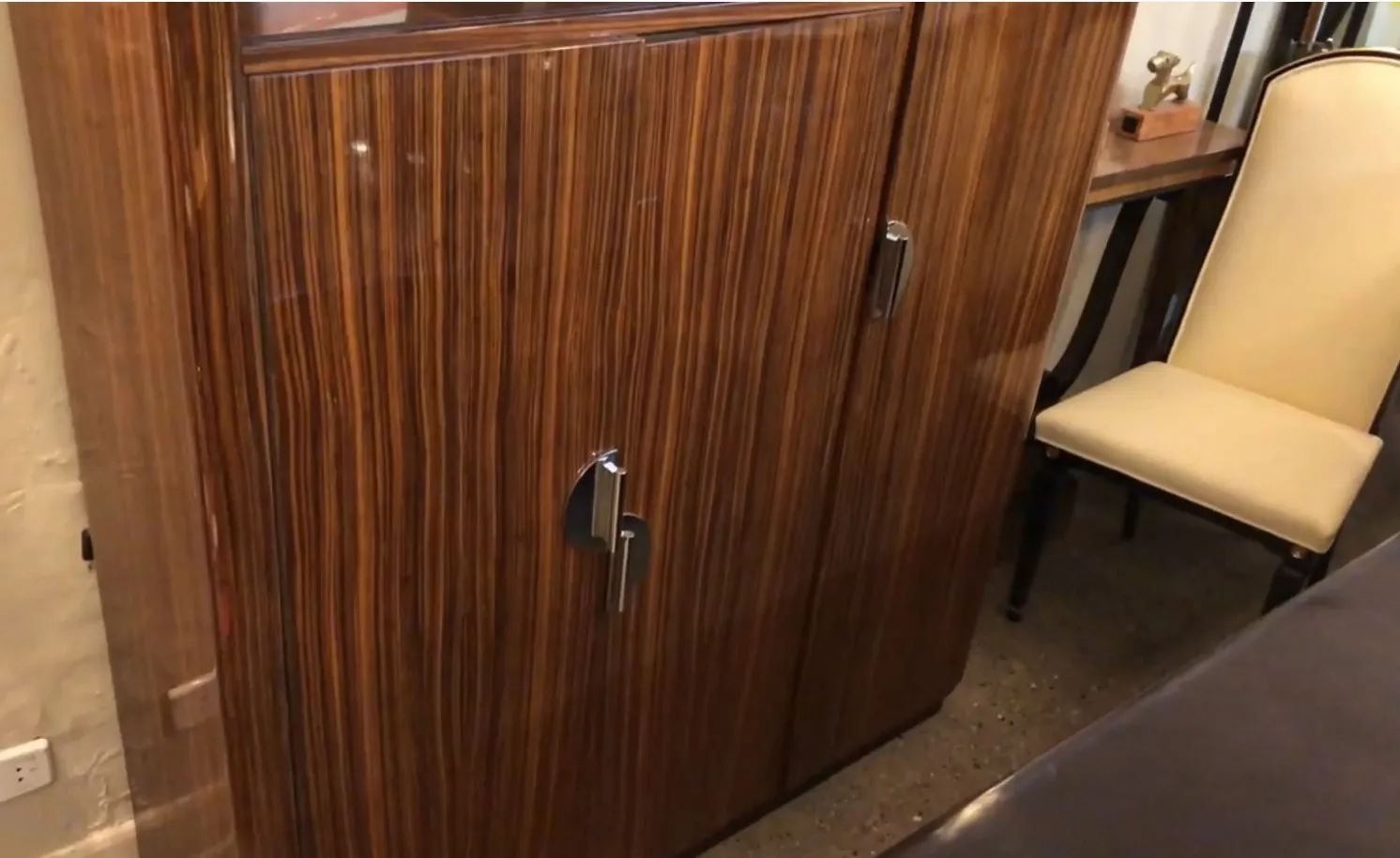 Estante de livros antigo com madeira escura e acabamentos brilhantes, em um ambiente clássico.