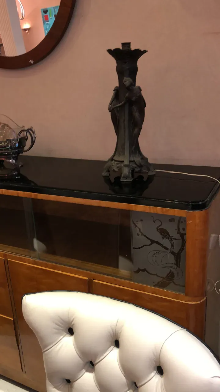 Estante de livros antigo com escultura decorativa no ambiente.