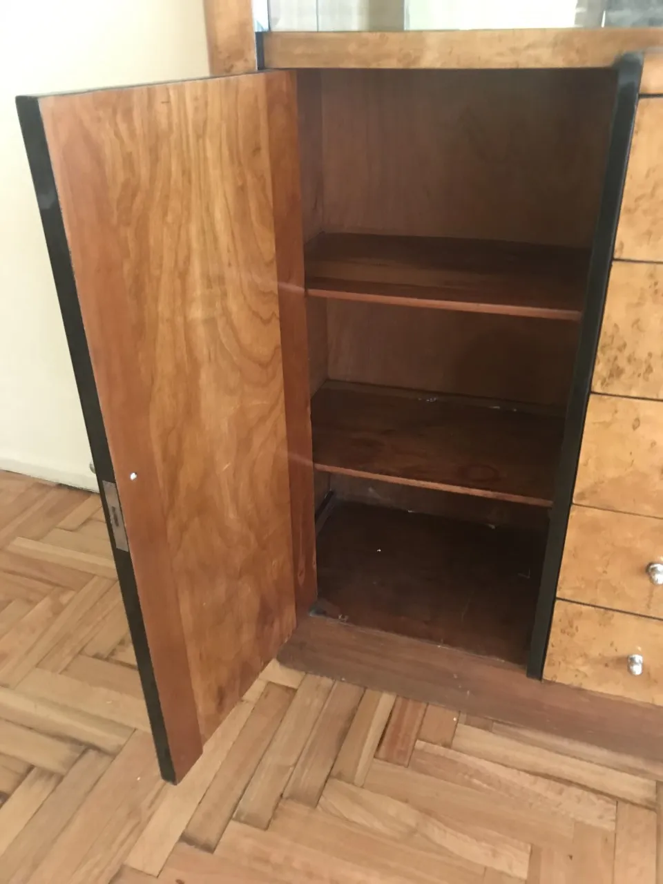 Antique bookcase with wooden shelves, door open, cozy atmosphere.
