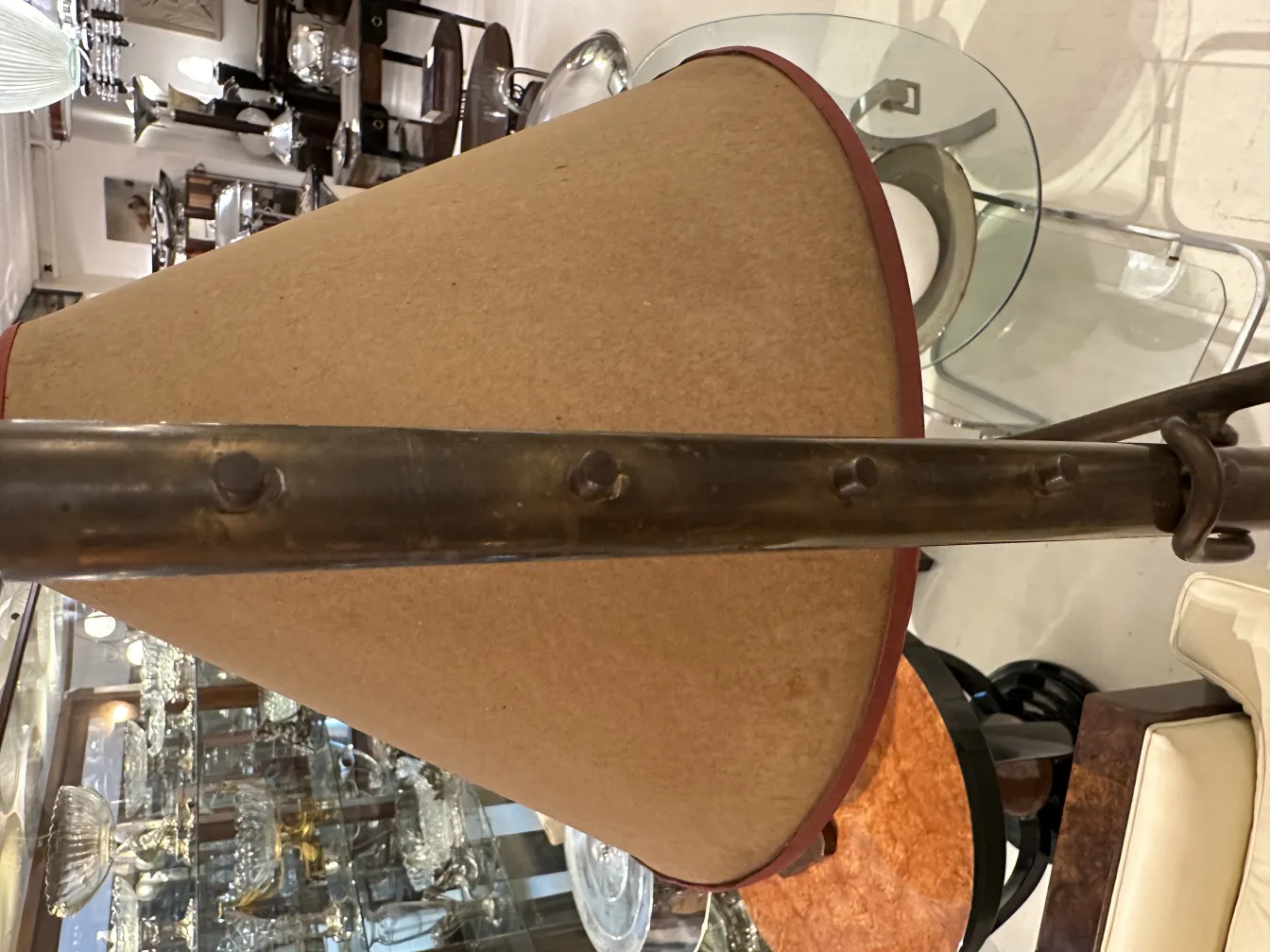 Antique floor lamp with conical shade and metal base in an elegant setting.