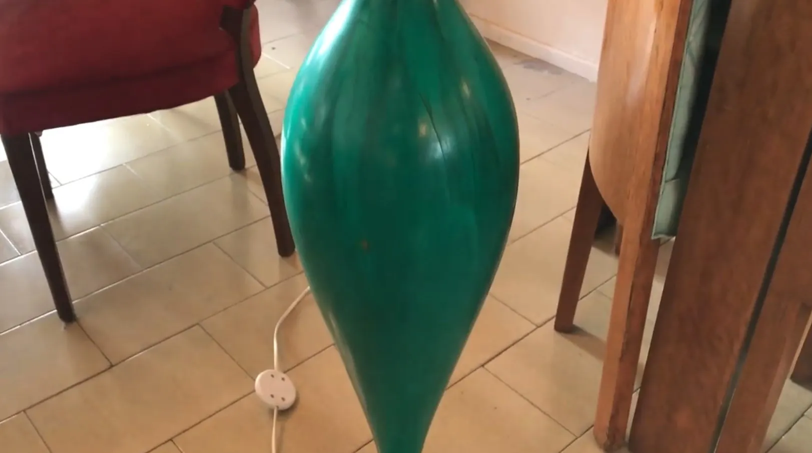 Lampada da terra antica di forma elegante in verde, accompagnata da un ambiente accogliente.