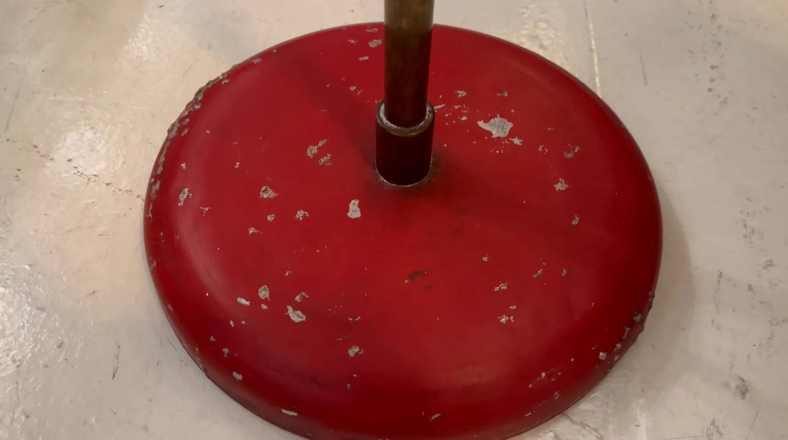 Lámpara de pie antigua con base roja y diseño desgastado, ideal para decoración.