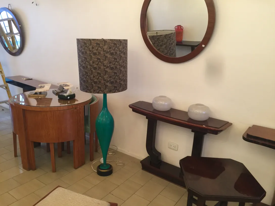 Ancienne torchiere avec base en forme de goutte, fond sombre et style décoratif. Atmosphère chaleureuse.