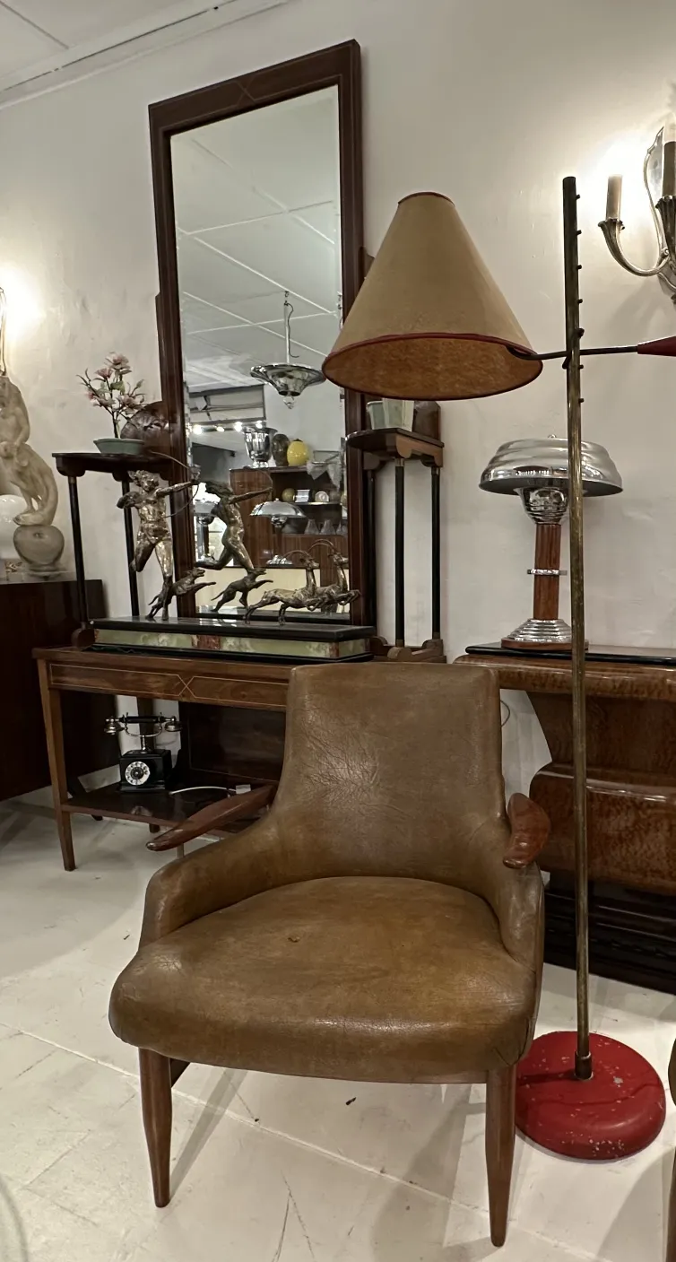 Luminária de pé antiga com cúpula em forma de cone e base vermelha, ambiente vintage com móveis de época.