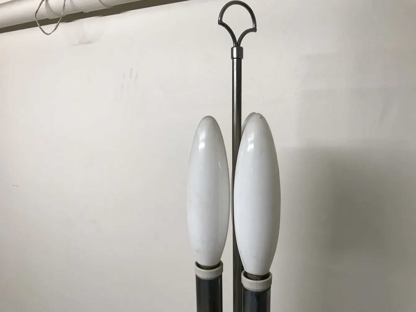 Torchiere antique avec deux ampoules blanches courbes dans un cadre neutre.