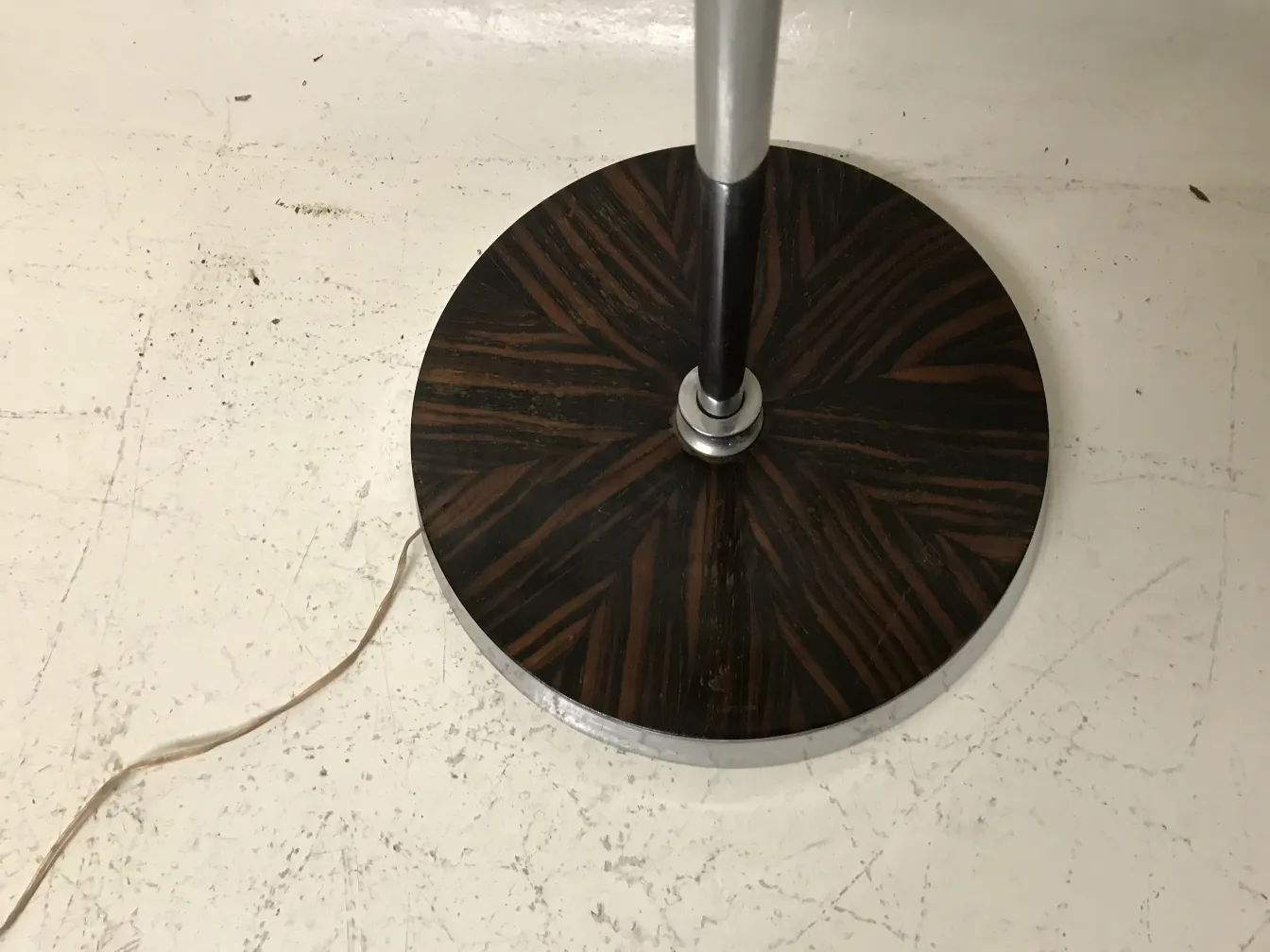 Lámpara de pie antigua con base decorada y cable visible.