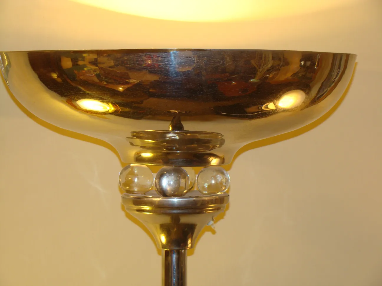 Antike Stehleuchte mit glänzenden Details und einem leuchtenden Schirm in einer gemütlichen Umgebung.